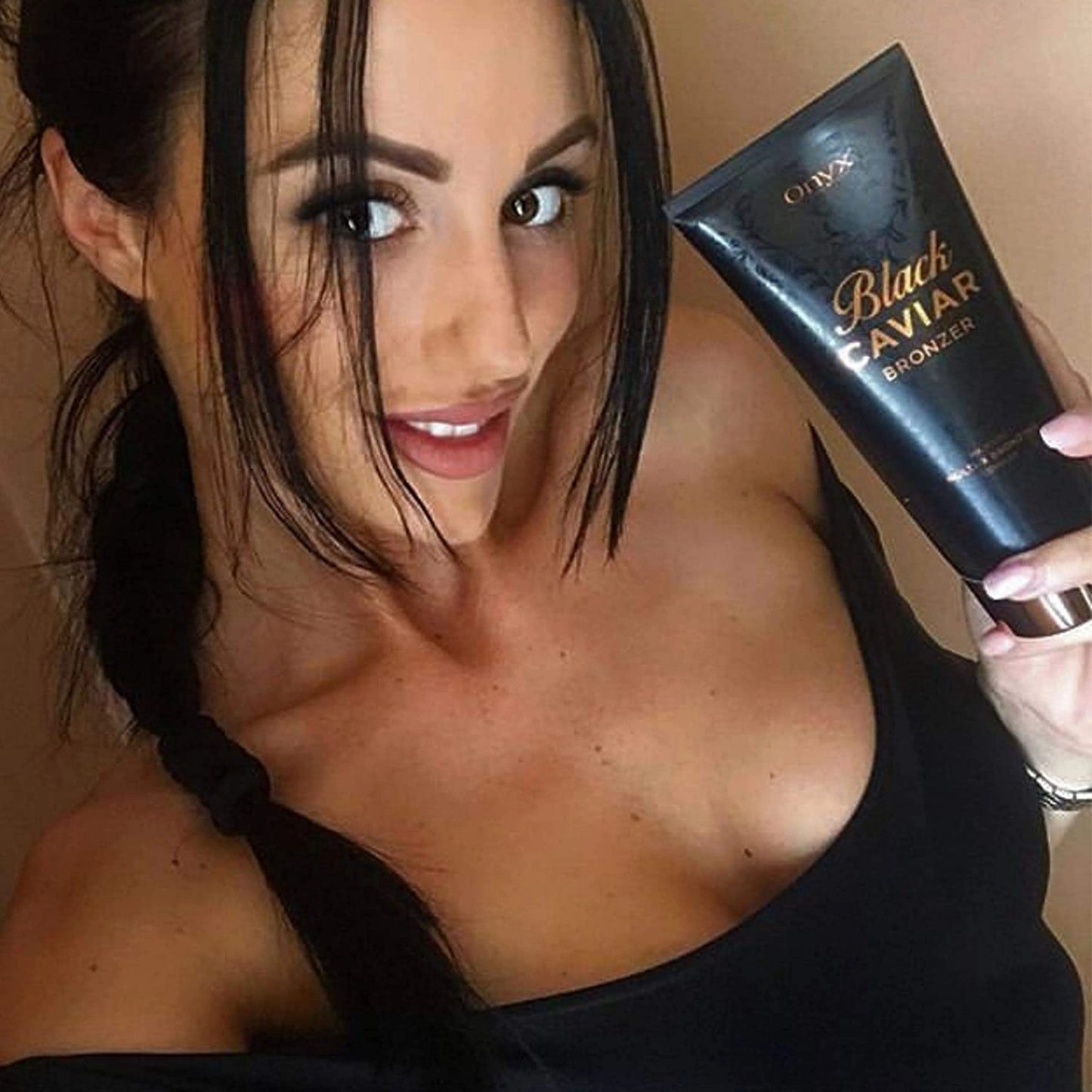 Frau mit dunklem Haar lächelt in die Kamera und präsentiert eine Tube Onyx Black Caviar Lotion