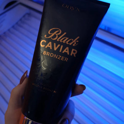 Onyx Black Caviar Lotion steht auf einer glänzenden Fläche, im Hintergrund ist eine geöffnete Solarbank mit Lichtreflexen zu sehen