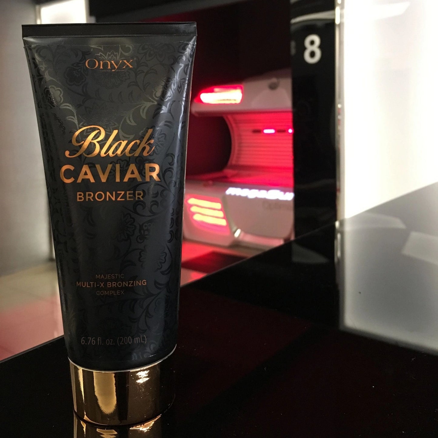 Schwarze Onyx Black Caviar Tube wird vor den beleuchteten Röhren einer Sonnenbank gehalten