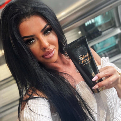 Frau mit dunklen Haaren hält Onyx Black Caviar Lotion in der Hand und macht ein Selfie in heller Umgebung