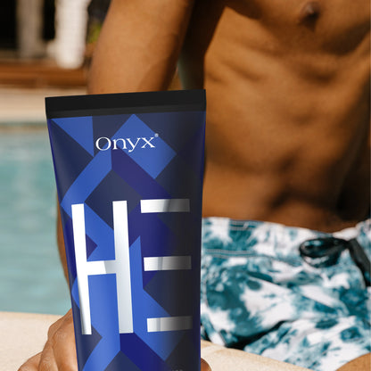 Nahaufnahme einer männlichen Hand, die eine Tube Onyx HE Bräunungsintensivierer neben einem Pool hält