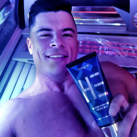 Ein Mann liegt in einem Solarium und hält eine Tube Onyx HE Bräunungsintensivierer, das Licht reflektiert auf seiner Haut